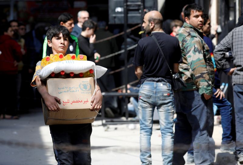 FILE PHOTO: Boy holds a cardboard box of food aid received from World Food Programme in Aleppo's Kalasa district