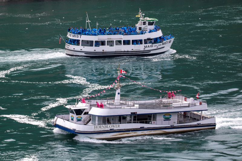 American tourist boat glides past a Canadian vessel limited to just six passengers in Niagara Falls