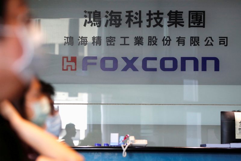 FILE PHOTO: People wear masks to protect themselves from coronavirus disease (COVID-19), while listening to the annual general meeting at the lobby of Foxconn's office in Taipei