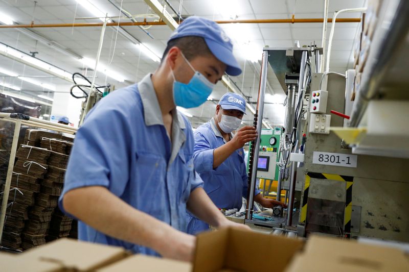 FILE PHOTO: Employees wearing masks work at a factory of the component maker SMC during a government organised tour of its facility following the outbreak of the coronavirus disease (COVID-19), in Beijing