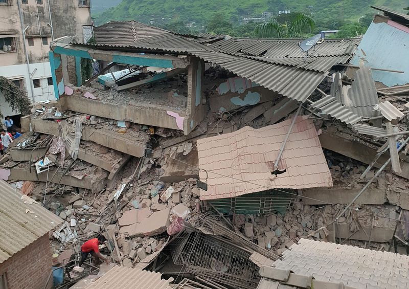A man removes the debris after a five-storey building collapsed in Raigad