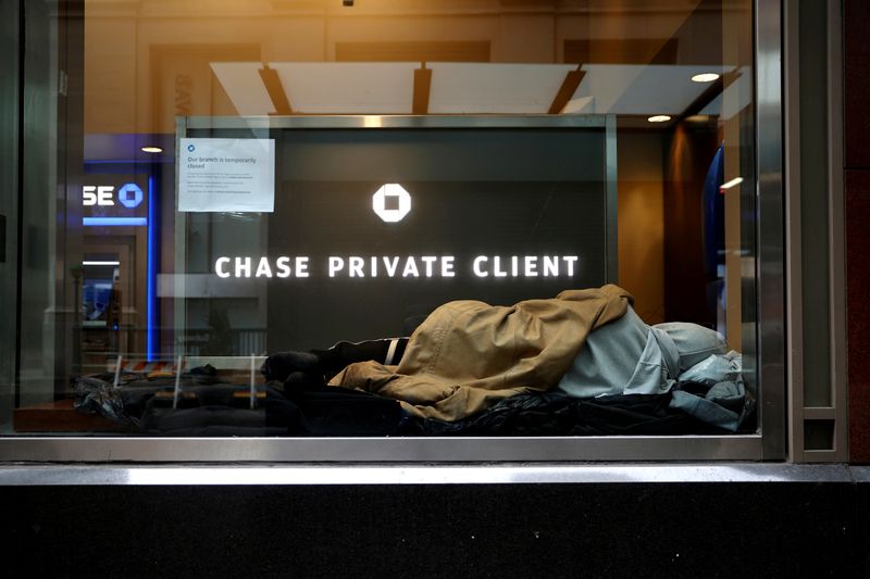 FILE PHOTO: A homeless man sleeps in a closed Chase bank branch on a nearly deserted Wall Street in Manhattan, in New York