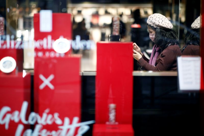 Tourist wears a protective mask as she looks at her mobile phone at the Galeries Lafayette department store in Paris as the country is hit by the new coronavirus