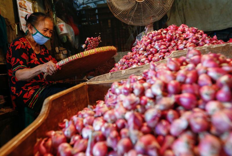 A worker wearing a protective face mask sorts onion at a traditional market amid the spread of the coronavirus disease (COVID-19)