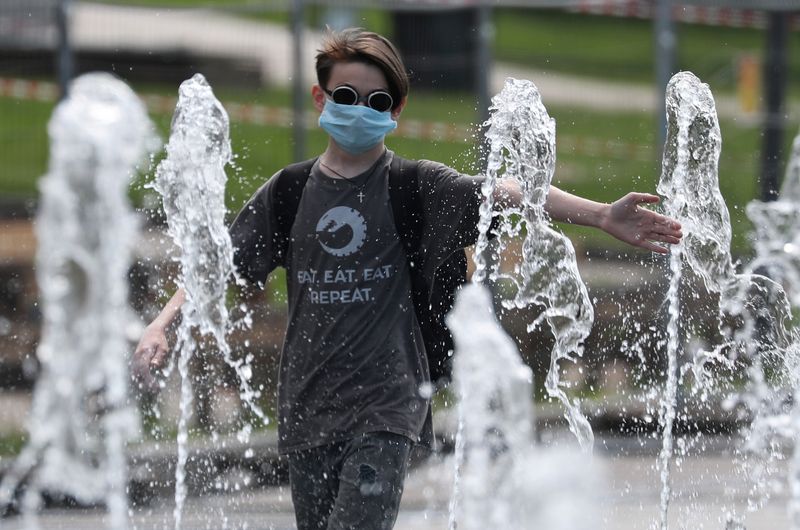 FILE PHOTO: A boy wearing a protective face mask plays in a fountain in Moscow