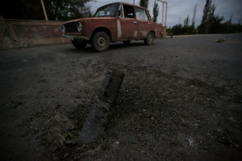 A car drives past the remains of spent ammunition following a recent shelling in Tartar