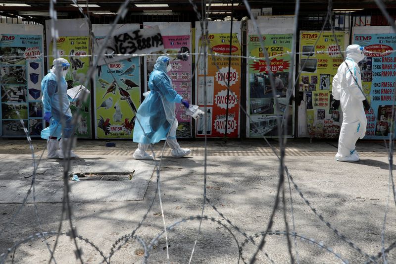 FILE PHOTO: Medical workers wearing protective suits pass by barbed wire at the red zone under enhanced lockdown, amid the coronavirus disease (COVID-19) outbreak, in Petaling Jaya