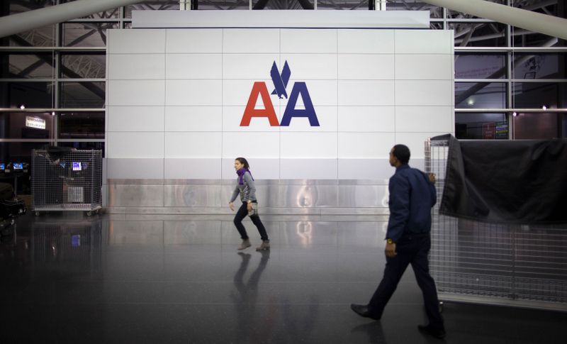 FILE PHOTO: People walk past an American Airlines logo at John F. Kennedy (JFK) airport in in New York