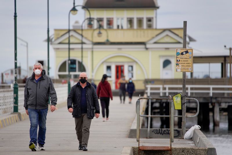 FILE PHOTO: Walkers wear protective face masks at St Kilda pier in Melbourne, the first city in Australia to enforce mask-wearing to curb a resurgence of COVID-19