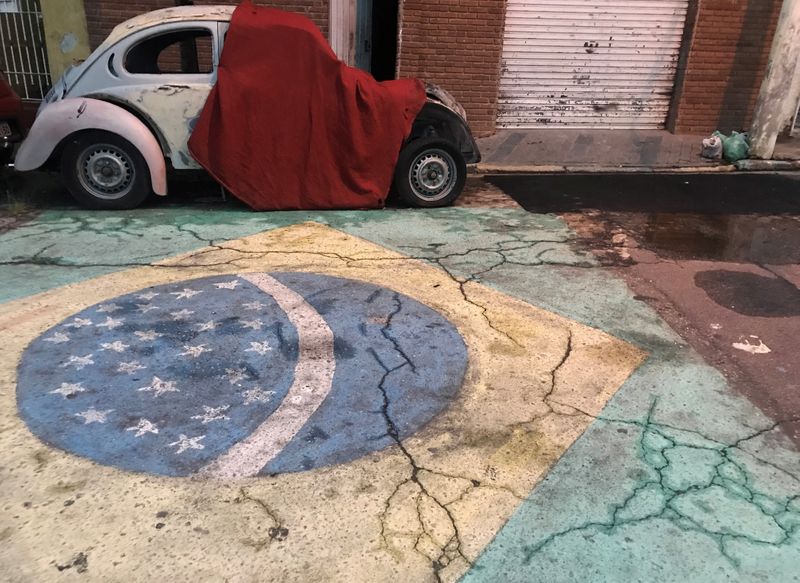 A Brazilian flag is seen painted on a street in front of a Volkswagen Beetle car in Sao Paulo