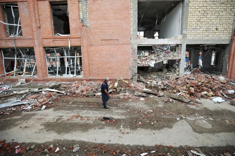 A man walks past a building damaged by recent shelling during a military conflict over the breakaway region of Nagorno-Karabakh, in Ganja