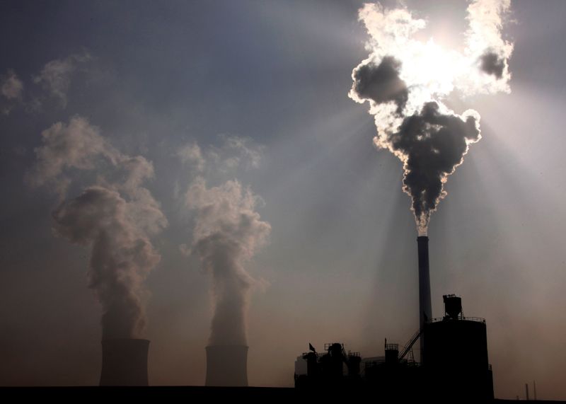 FILE PHOTO: A coal-burning power plant can be seen behind a factory in the city of Baotou