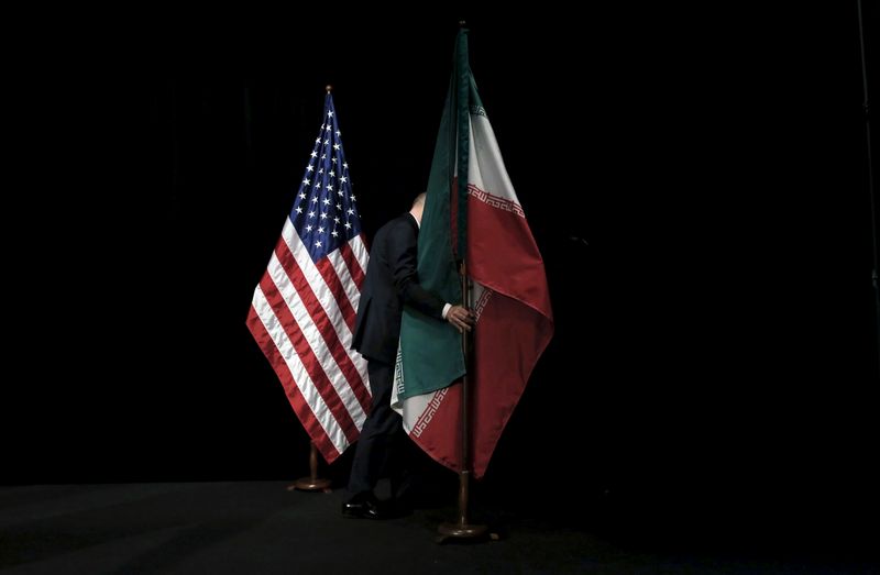 A staff member removes the Iranian flag from the stage after a group picture with foreign ministers and representatives during the Iran nuclear talks at the Vienna International Center in Vienna