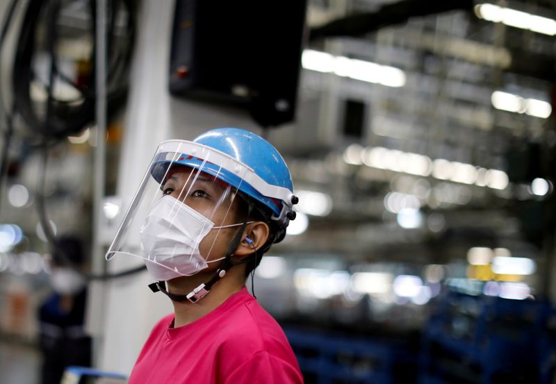 FILE PHOTO: An employee wearing a protective face mask and face guard works on the automobile assembly line during the outbreak of the coronavirus disease (COVID-19) at the factory of Mitsubishi Fuso Truck and Bus Corp. in Kawasaki