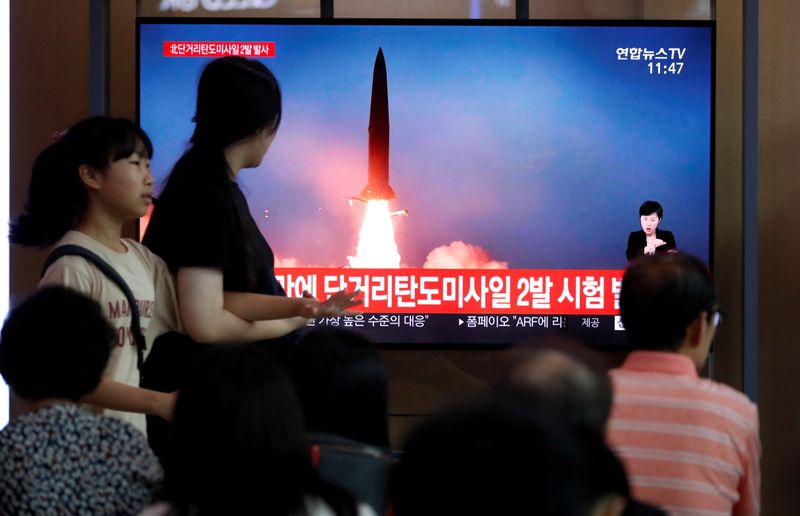 FILE PHOTO: People watch a television showing a file picture of a North Korean missile for a news report on North Korea firing short-range ballistic missiles, in Seoul, South Korea