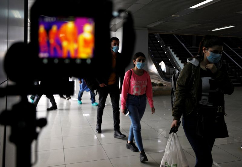 Passengers walk past a thermal scanner as part of security measures to avoid coronavirus in the country