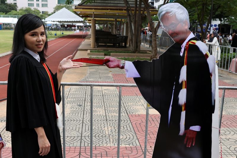 A student stands next to a cardboard figure of Somsak Jeamteerasakul, an exiled Thai academic, before a graduation ceremony, which some students have boycotted because it is led by King Maha Vajiralongkorn, at Thammasat University in Bangkok