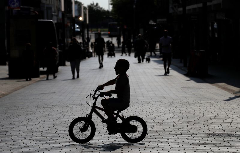 FILE PHOTO: A child cycles his bike across a quiet shopping street following the outbreak of the coronavirus disease (COVID-19) in St Helens