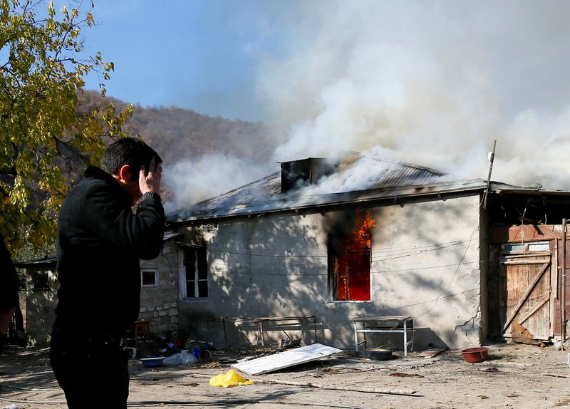 A man reacts as he stands near a house set on fire by departing Ethnic Armenians in the village of Cherektar, in the region of Nagorno-Karabakh