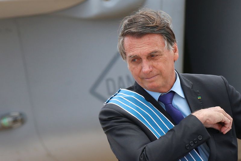FILE PHOTO: Brazil's President Jair Bolsonaro looks on in front of a Brazilian Air Force F-39E Gripen fighter during a ceremony of Aviator's Day at Brasilia Air Base