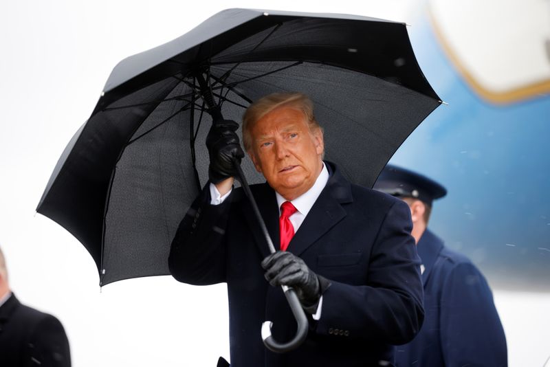 U.S. President Donald Trump holds an umbrella as he arrives for a campaign rally, at Oakland County International Airport