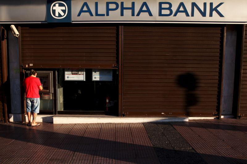 FILE PHOTO: A man withdraws money at an Alpha Bank branch ATM in central Athens