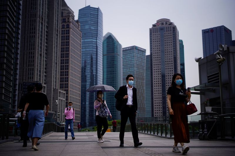People wearing protective face masks walk past office buildings in Lujiazui financial district in Pudong, in Shanghai