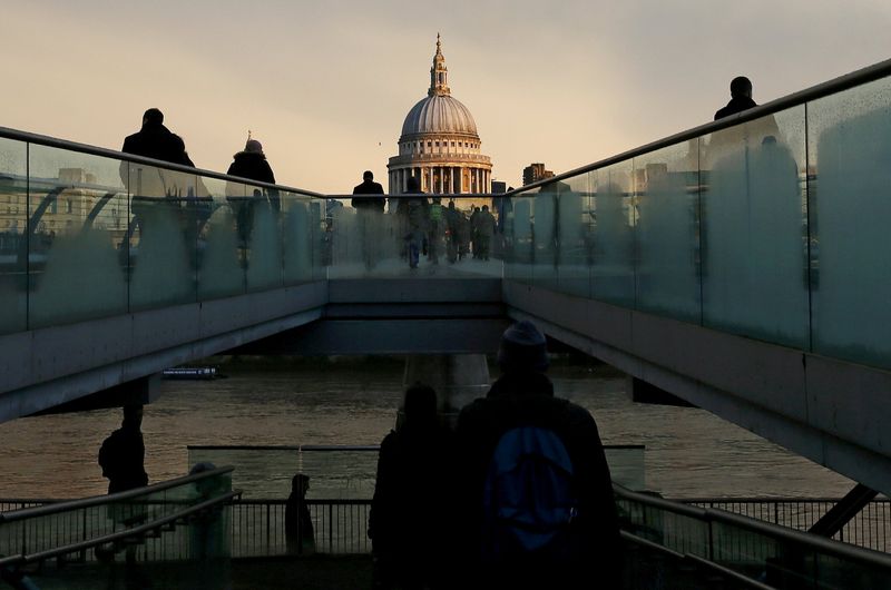 FILE PHOTO: File photo of city workers walking towards St Paul's Cathedral as they cross the Millennium footbridge during sunrise in central London