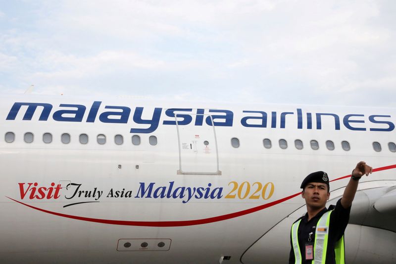 FILE PHOTO: An airport employee beside a Malaysia Airlines plane at Kuala Lumpur International Airport