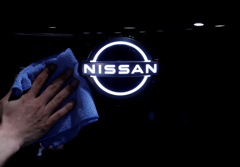 FILE PHOTO: A man wipes the brand logo of Nissan Motor Corp. on the front nose section of the company's new Ariya all-battery SUV during a press preview in Yokohama