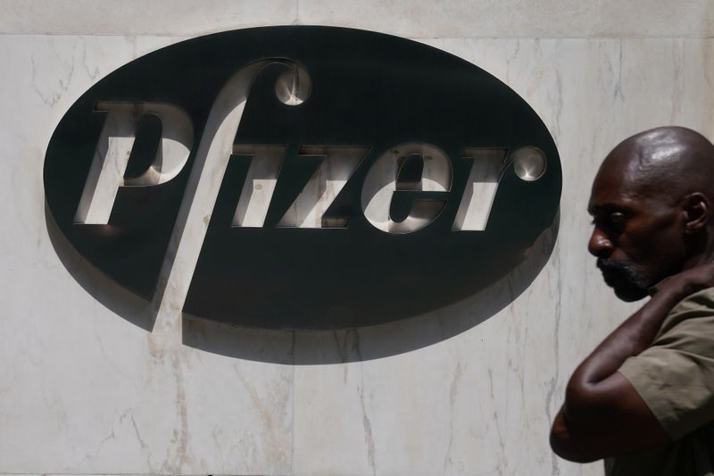 A man walks past a sign outside Pfizer Headquarters in the Manhattan borough of New York City