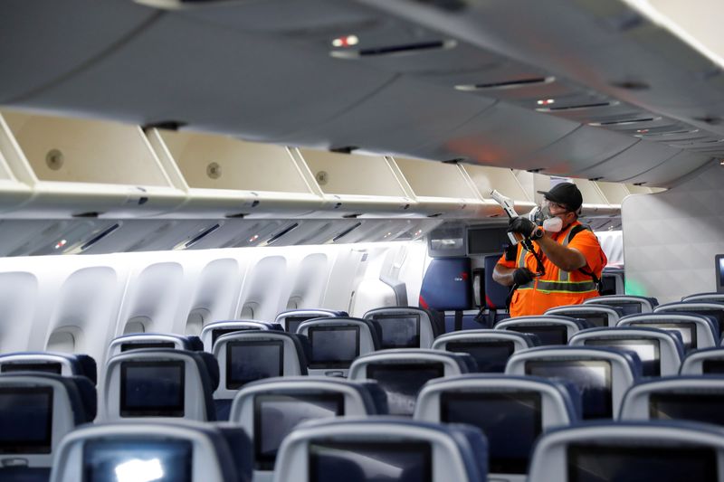 A Delta Air Lines pre-flight cleaning crew member uses an electrostatic disinfection device to clean an aircraft at JFK International Airport in New York