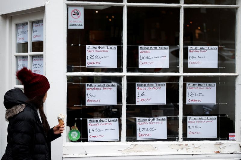 A person looks at adverts in the window of a job agency in London