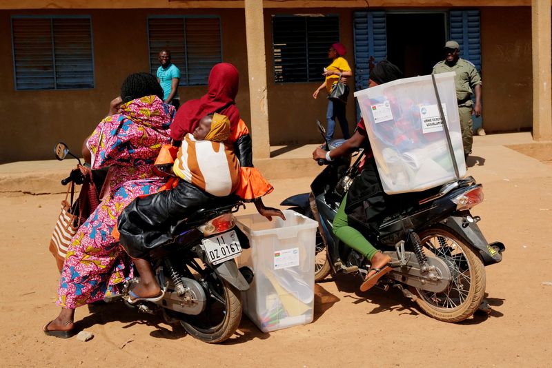 Electoral workers transport ballot boxes on their motorcycles as they arrive to prepare a polling station ahead of the presidential and legislative elections, in Ouagadougou,