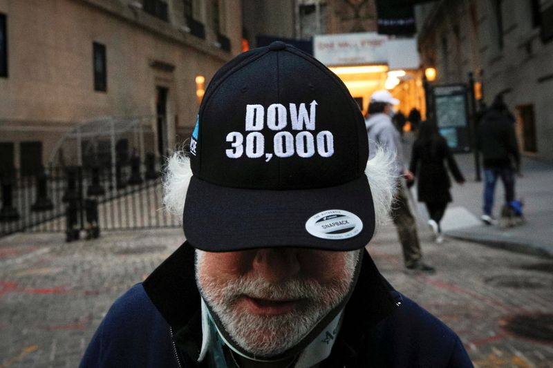 Trader Peter Tuchman wears a DOW 30,000 hat as he greets friends outside the New York Stock Exchange (NYSE) in New York