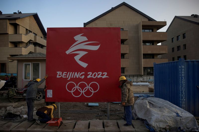 FILE PHOTO: Workers move a sign at the Olympic Village in the Chongli district of Zhangjiakou