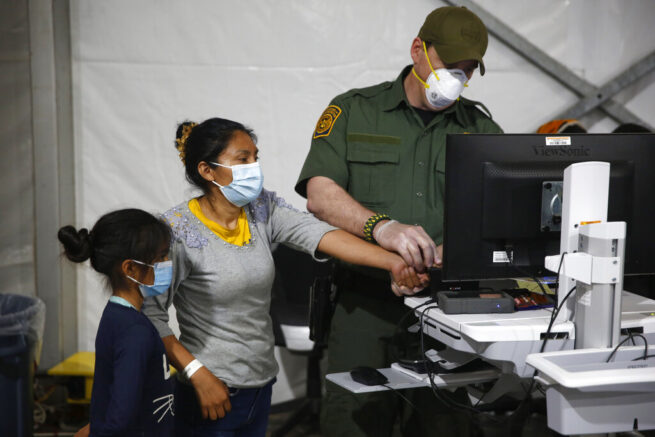 A migrant and her daughter have their biometric data entered at the intake area of the Donna Department of Homeland Security holding facility, the main detention center for unaccompanied children in the Rio Grande Valley, in Donna, Texas, Tuesday, March 30, 2021. (AP Photo/Dario Lopez-Mills, Pool)