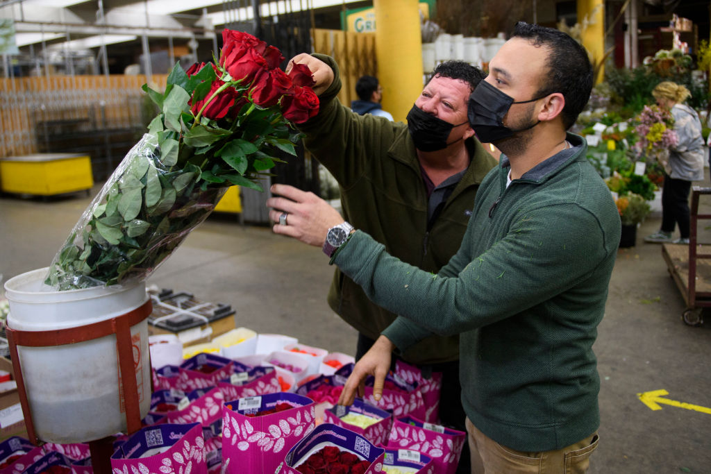 Merchant Jesus Barajas (C) wears a face mask as he shows long stem roses for sale ahead of the Valentine's Day holiday at the Southern California Flower Market on February 12, 2021 in Los Angeles, California. - While some florists note an increased demand for socially distant gifts, the Covid-19 pandemic has impacted global supply chains and shut down most large events including weddings where flowers are popular. The Valentine's Day and Mother's Day holidays are historically the two busiest days of the year for floral businesses. (Photo by Patrick T. FALLON / AFP) (Photo by PATRICK T. FALLON/AFP via Getty Images)