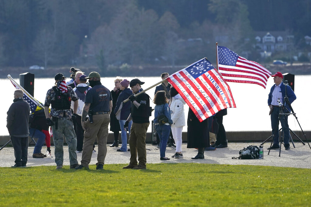 A person holds a flag with some of the words of the Second Amendment to the U.S. Constitution on it, Saturday, March 13, 2021, during a rally at a park in Olympia, Wash., protesting business and school closures and other restrictions related to the COVID-19 pandemic. Several dozen people also gathered earlier at the Capitol in support of open-carry gun rights. (AP Photo/Ted S. Warren)