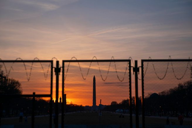 The Washington Monument is seen at sunset from behind a barbed wire fence perimeter that surrounds the U.S. Capitol on March 8, 2021 in Washington, DC. The House is scheduled to begin vote on the Senate's Covid-19 relief bill later this week. (Photo by Sarah Silbiger/Getty Images)