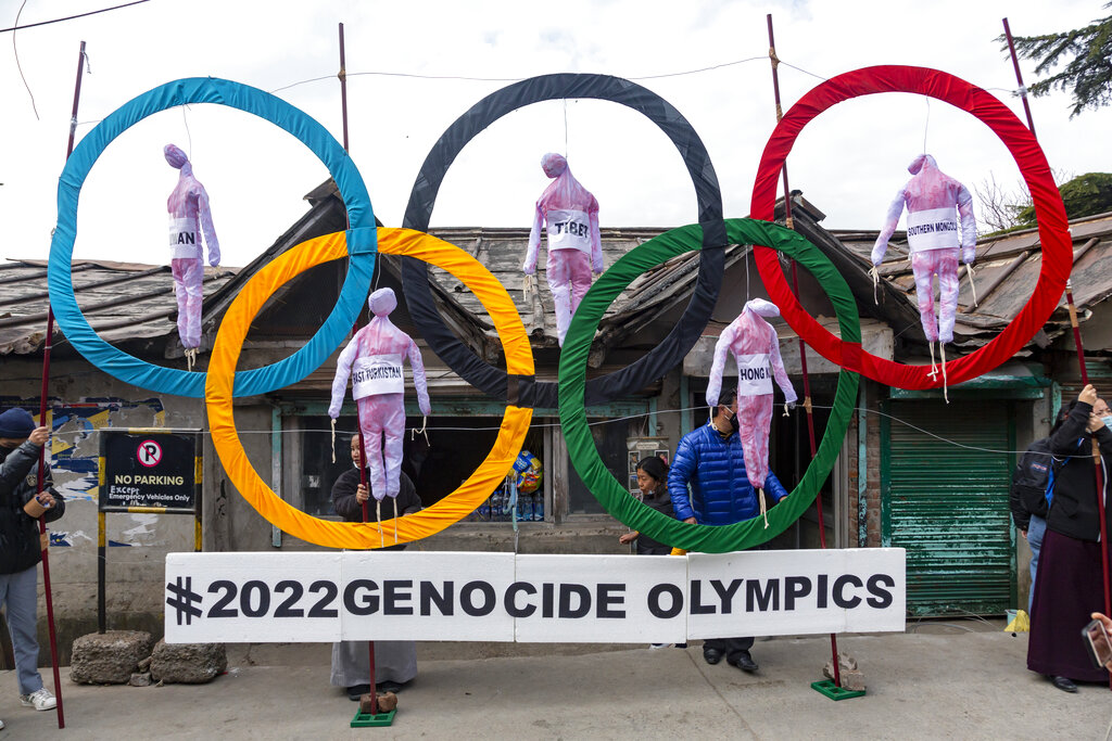 FILE - In this Feb. 3, 2021, file photo, exile Tibetans use the Olympic Rings as a prop as they hold a street protest against the holding of 2022 Winter Olympics in Beijing in Dharmsala, India. Some kind of boycott is almost sure to affect next year’s Beijing Winter Olympics. It’s driven by the widely reported internment of several million Muslim Uyghurs and other ethnic minorities in China, which has been termed a genocide by numerous governments and human rights groups. (AP Photo/Ashwini Bhatia, File)