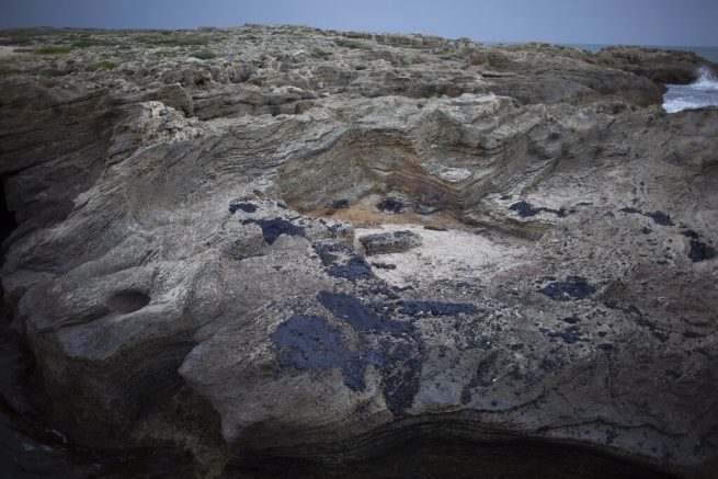 FILE - In this Tuesday, Feb. 23, 2021 file photo, tar is stuck on rocks after an oil spill in the Mediterranean Sea, at Tel-Dor Nature Reserve, in Nahsholim, Israel. Israeli authorities said they believed a tanker suspected of smuggling oil from Iran to Syria was responsible for spilling tons of crude into the Mediterranean last month, causing one of Israel's worst environmental disasters. (AP Photo/Ariel Schalit, File)