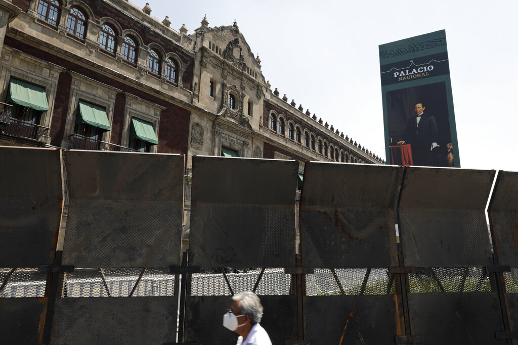 People walk past a perimeter fence set up in front of the National Palace in preparation for the upcoming International Women's Day demonstration, in Mexico City, Friday, March 5, 2021. The colonial-era palace is located on the city’s vast central plaza, and is where President Andrés Manuel López Obrador lives and works. (AP Photo/Eduardo Verdugo)
