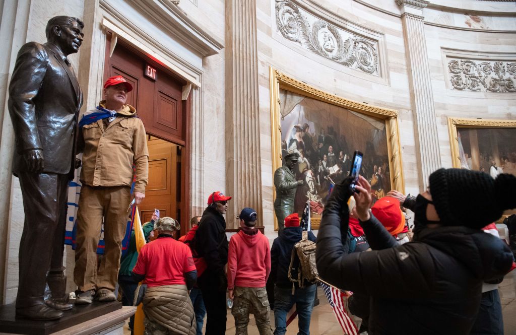 Supporters of US President Donald Trump pose with statues inside the Rotunda after breaching the US Capitol in Washington, DC, January 6, 2021. - The demonstrators breeched security and entered the Capitol as Congress debated the 2020 presidential election Electoral Vote Certification. (Photo by SAUL LOEB / AFP) (Photo by SAUL LOEB/AFP via Getty Images)