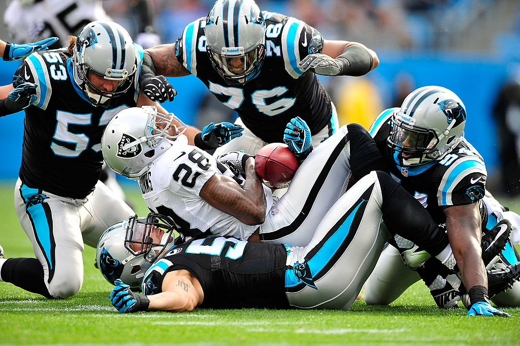 CHARLOTTE, NC - DECEMBER 23: Jason Phillips #53, Greg Hardy #76, Jason Williams #54 and Jordan Senn #57 of the Carolina Panthers tackle Phillip Adams #28 of the Oakland Raiders during play at Bank of America Stadium on December 23, 2012 in Charlotte, North Carolina. (Photo by Grant Halverson/Getty Images)