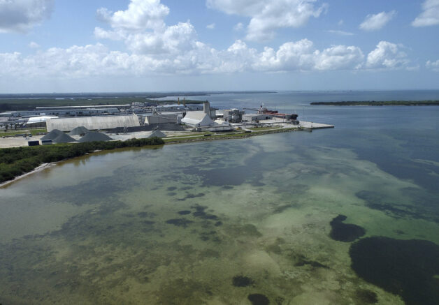 This photo taken by a drone shows the old Piney Point phosphate mine, Saturday, April 3, 2021 in Bradenton, Fla. Florida Gov. Ron DeSantis declared a state of emergency Saturday after a significant leak at a large pond of wastewater threatened to flood roads and burst a system that stores polluted waters. The pond where the leak was discovered is at the old Piney Point phosphate mine, sitting in a stack of phosphogypsum, a waste product from manufacturing fertilizer that is radioactive. (Tiffany Tompkins/The Bradenton Herald via AP)