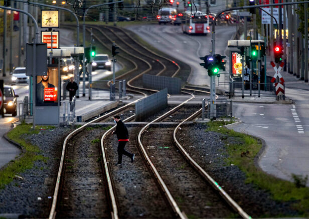 A man crosses tram rails in Frankfurt, Germany, before curfew on Saturday, April 24, 2021. From the weekend on a curfew becomes effective to avoid the outspread of the coronavirus. (AP Photo/Michael Probst)