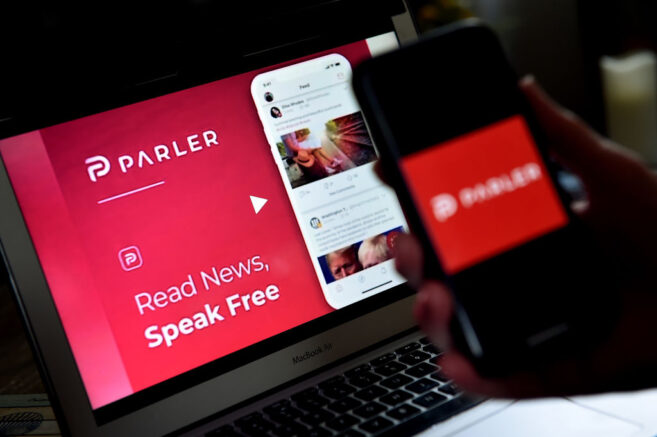 This illustration picture shows social media application logo from Parler displayed on a smartphone with its website in the background in Arlington, Virginia on July 2, 2020. - Amid rising turmoil in social media, recently formed social network Parler is gaining with prominent political conservatives who claim their voices are being silenced by Silicon Valley giants. Parler, founded in Nevada in 2018, bills itself as an alternative to "ideological suppression" at other social networks. (Photo by Olivier DOULIERY / AFP) (Photo by OLIVIER DOULIERY/AFP via Getty Images)