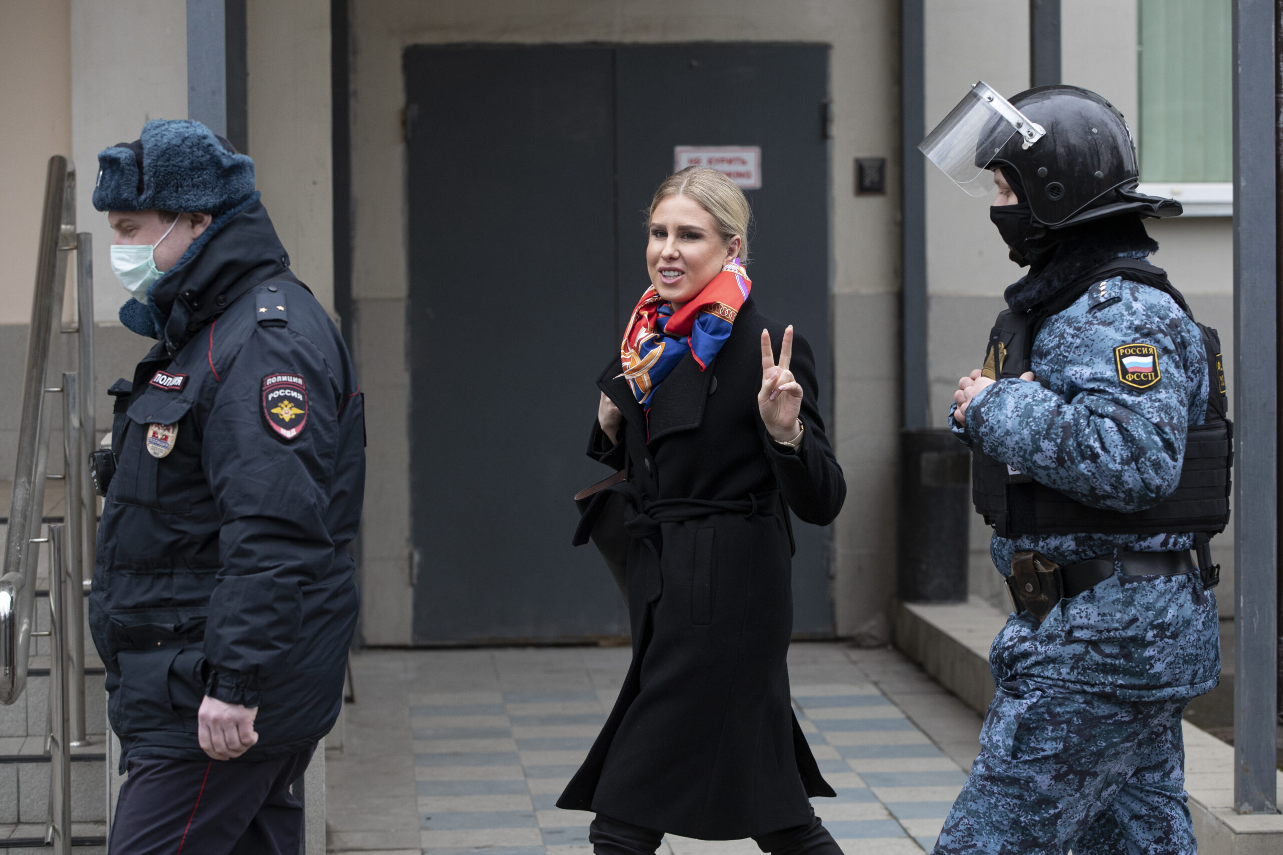 Russian opposition activist Lyubov Sobol, center, gestures as she walks to the court escorted by police and Russian Federal Bailiffs service officers in Moscow, Russia, Monday April 5, 2021. A Moscow court will start considering the case against Navalny ally Lyubov Sobol, who is charged with unlawful entry into a dwelling. In December Sobol rang the doorbell of a flat of a relative of an alleged FSB agent Konstantin Kudryavtsev, whom Navalny accused of his poisoning. (AP Photo/Pavel Golovkin)