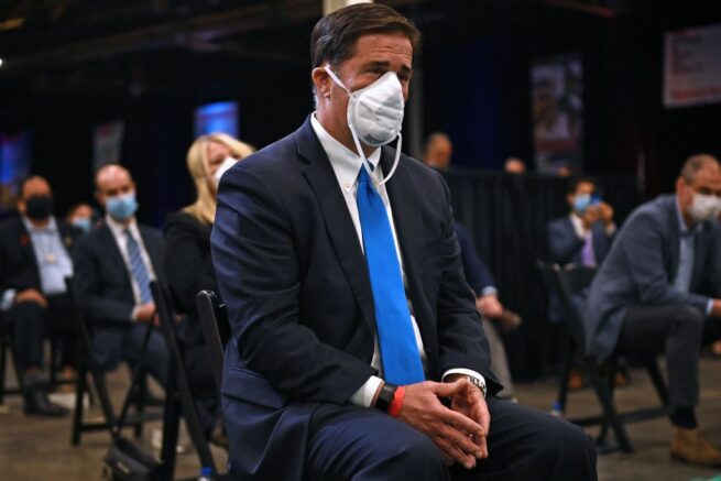 Arizona Governor Doug Ducey (C) listens as US President Donald Trump speaks during a tour of a Honeywell International plant that manufactures personal protective equipment in Phoenix, Arizona on May 5, 2020. (Photo by Brendan Smialowski / AFP) (Photo by BRENDAN SMIALOWSKI/AFP via Getty Images)